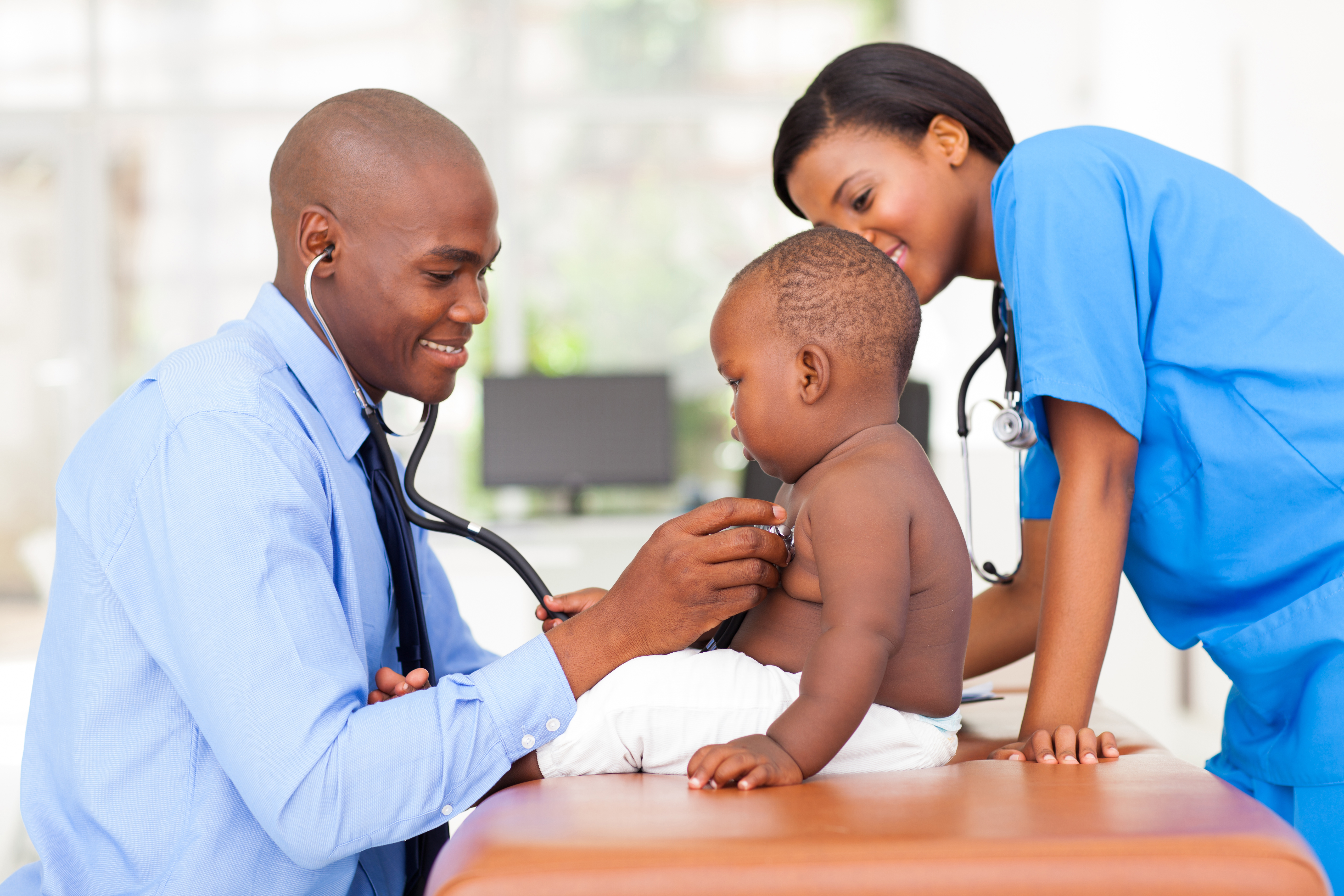 african american male pediatric doctor examining baby boy with female nurse